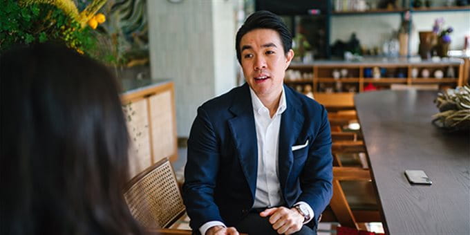 Ein Mann sitzt auf einem Stuhl und unterhält sich Ein Mann sitzt auf einem Stuhl und unterhält sich