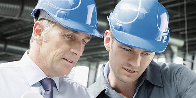 Zwei Männer mit Schutzhelm unterhalten sich auf einer Baustelle. Zwei Männer mit Schutzhelm unterhalten sich auf einer Baustelle.