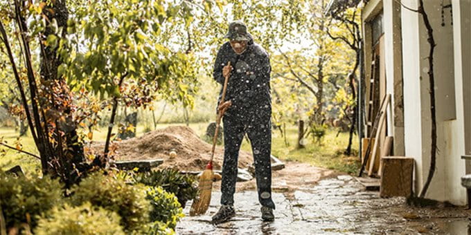 Mann wischt nasse Terasse nach Dauerregen Mann wischt nasse Terasse nach Dauerregen