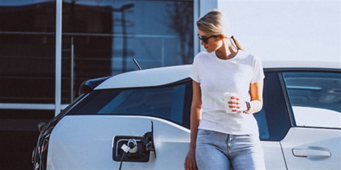 Frau vor Elektrofahrzeug Frau vor Elektrofahrzeug