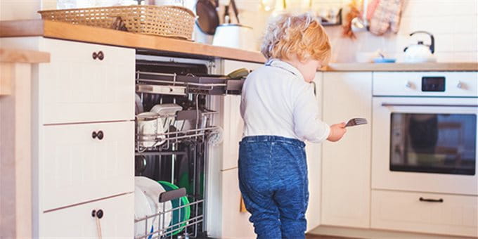 Ein Kind steht auf der Abwaschmaschinen Türe Ein Kind steht auf der Abwaschmaschinen Türe