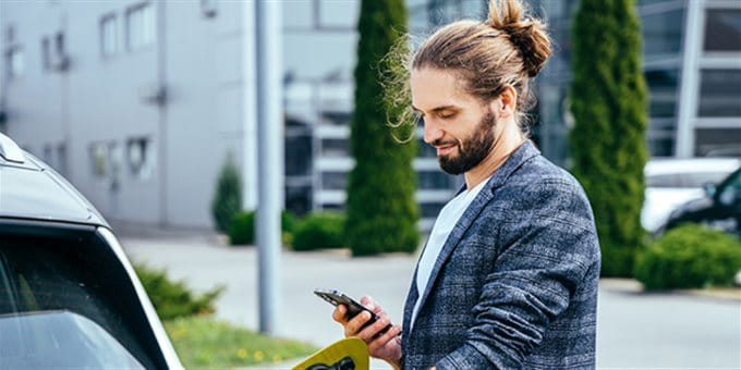Mann mit Handy an Ladestation Mann mit Handy an Ladestation