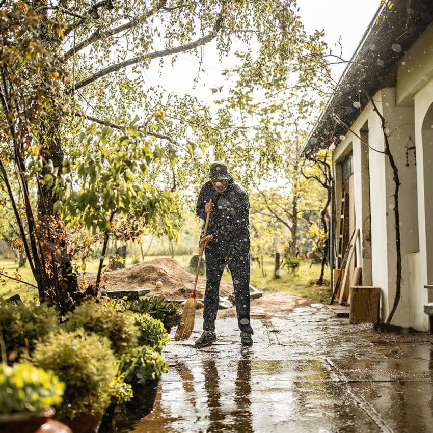 Un homme nettoie une terrasse mouillée après une pluie persistante Un homme nettoie une terrasse mouillée après une pluie persistante