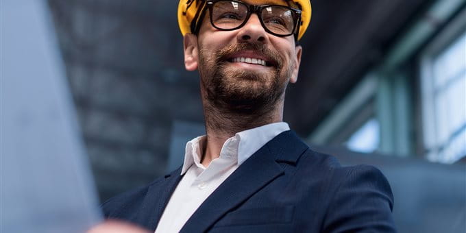 Mann mit gelbem Helm und Plan auf Baustelle Mann mit gelbem Helm und Plan auf Baustelle