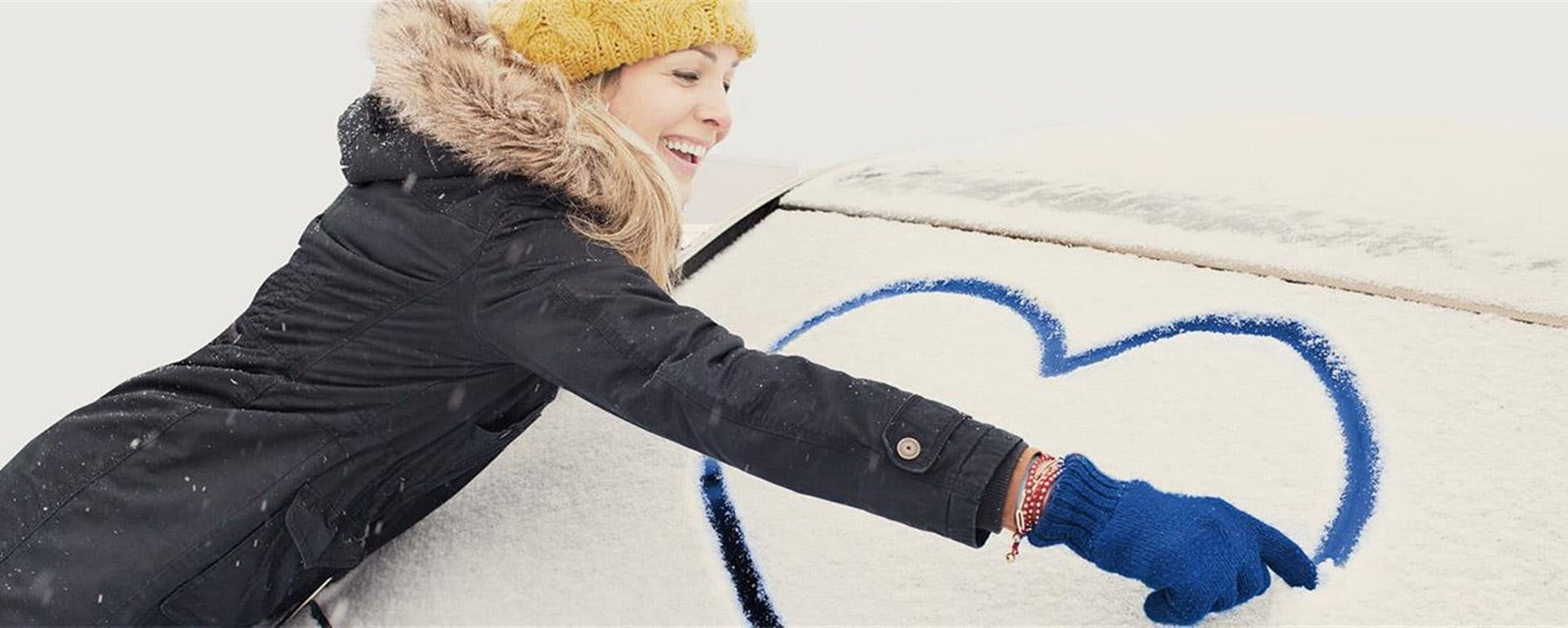 Frau malt Herz auf Autoscheibe Frau malt Herz auf Autoscheibe