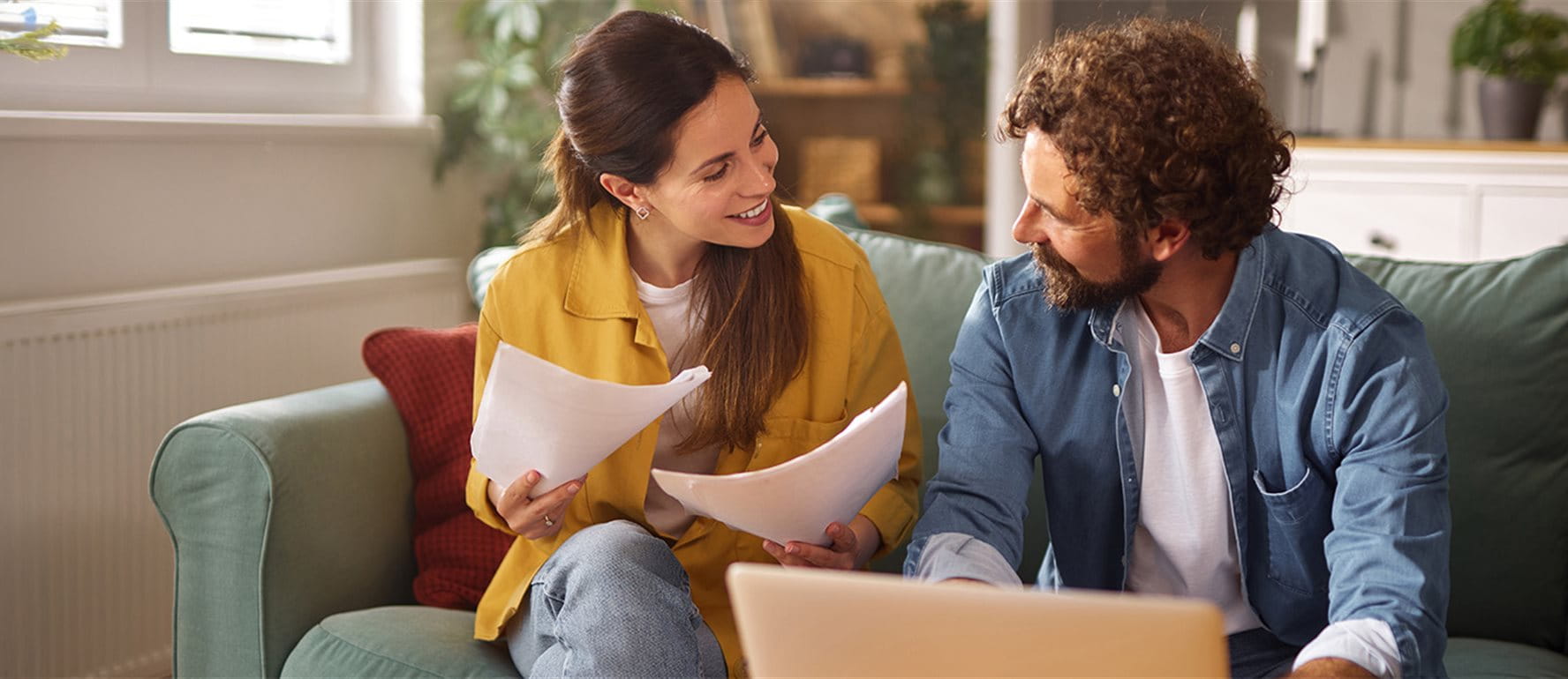 A couple is sitting on a couch and discussing documents A couple is sitting on a couch and discussing documents