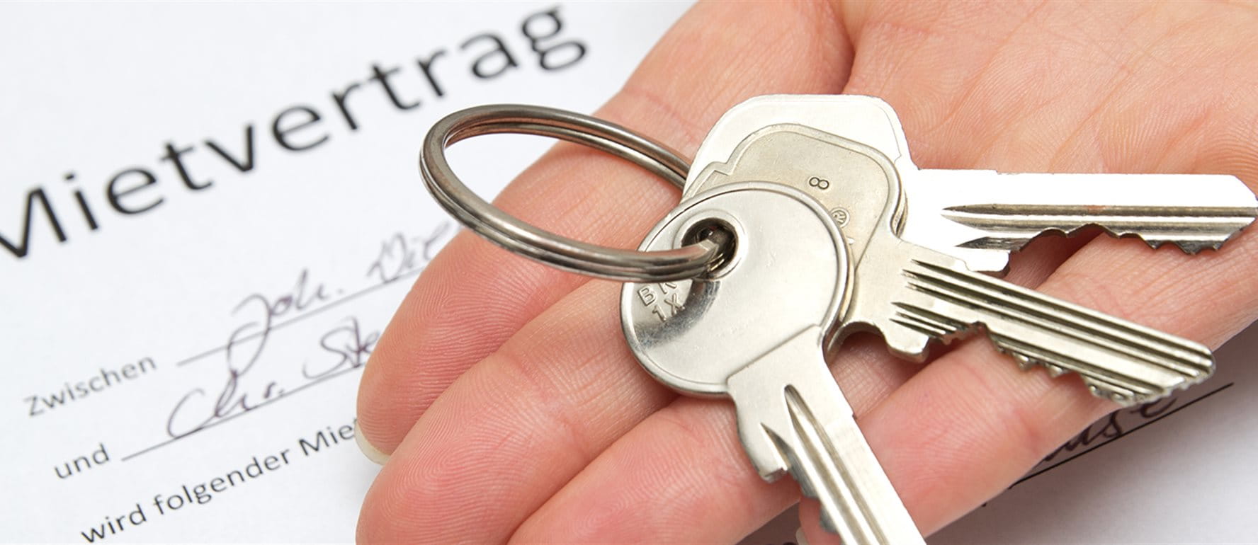 A bunch of keys lies in an open hand above a rental agreement A bunch of keys lies in an open hand above a rental agreement