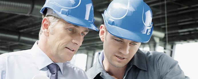 Two men with helmets talking at a construction site. Two men with helmets talking at a construction site.