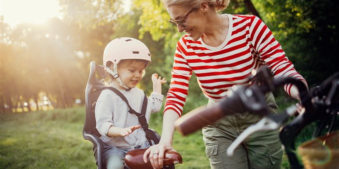 A mother is riding a bicycle with her child A mother is riding a bicycle with her child