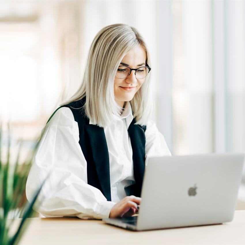 A professional working on a laptop in a bright, modern office space. A professional working on a laptop in a bright, modern office space.