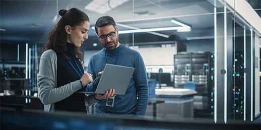 A woman and a man look into a laptop together A woman and a man look into a laptop together