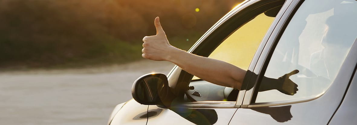 A hand giving a thumbs-up is sticking out of a car window. A hand giving a thumbs-up is sticking out of a car window.