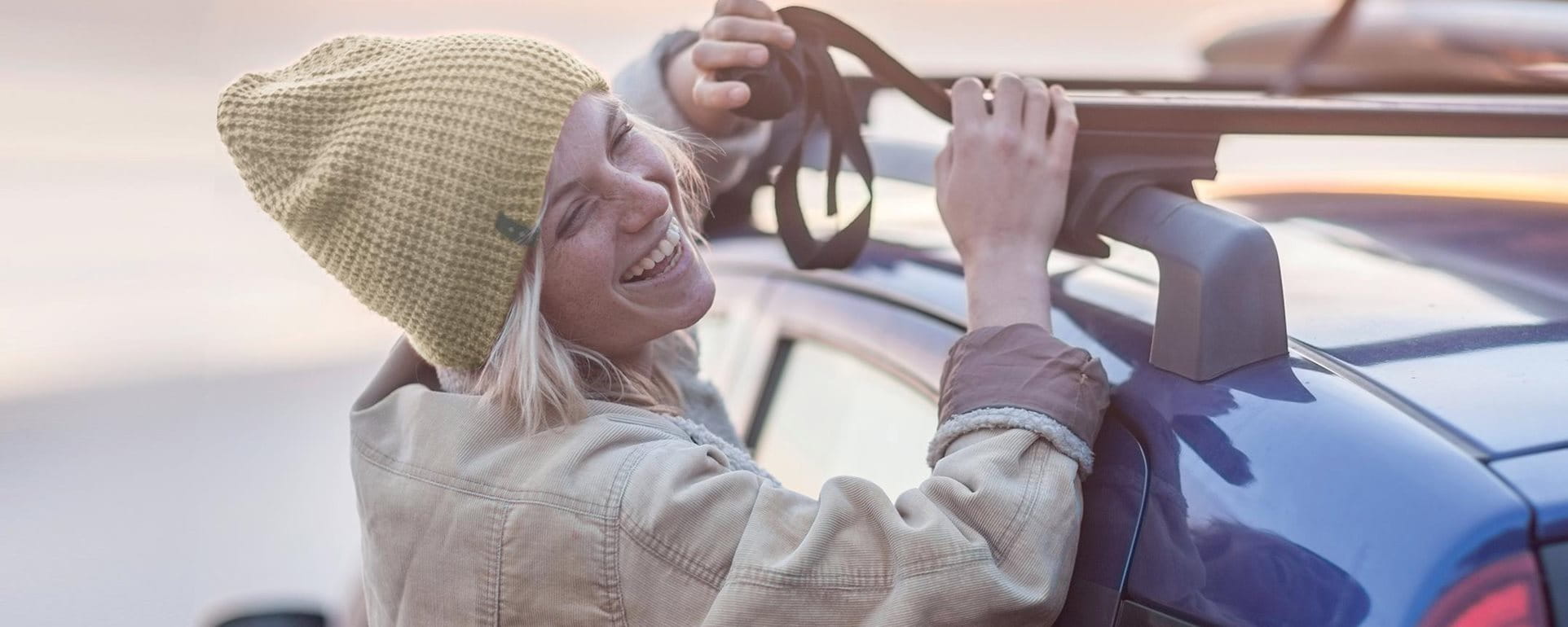 Young woman attaches surfboard to the roof of the car Young woman attaches surfboard to the roof of the car