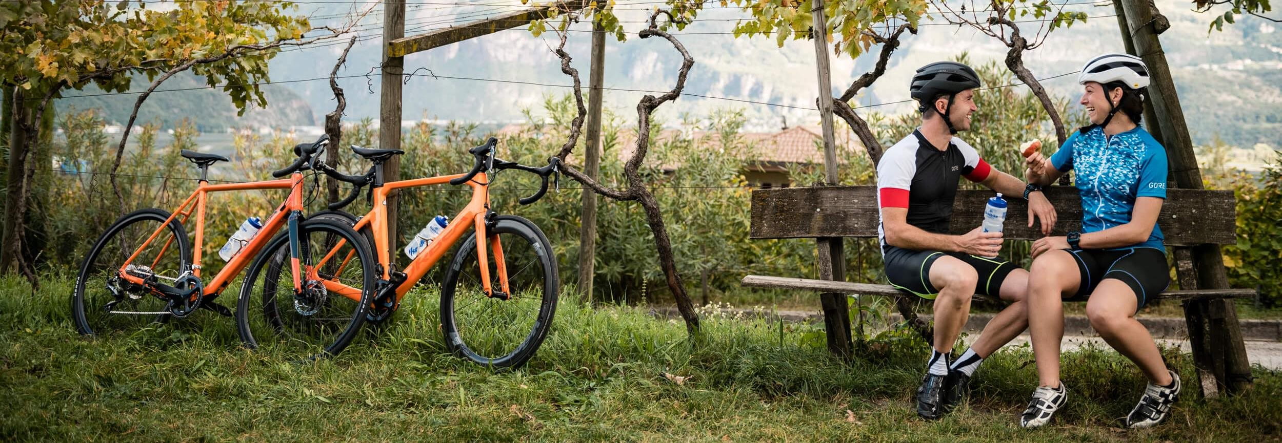 Couple sit on bench next to their racing bikes Couple sit on bench next to their racing bikes