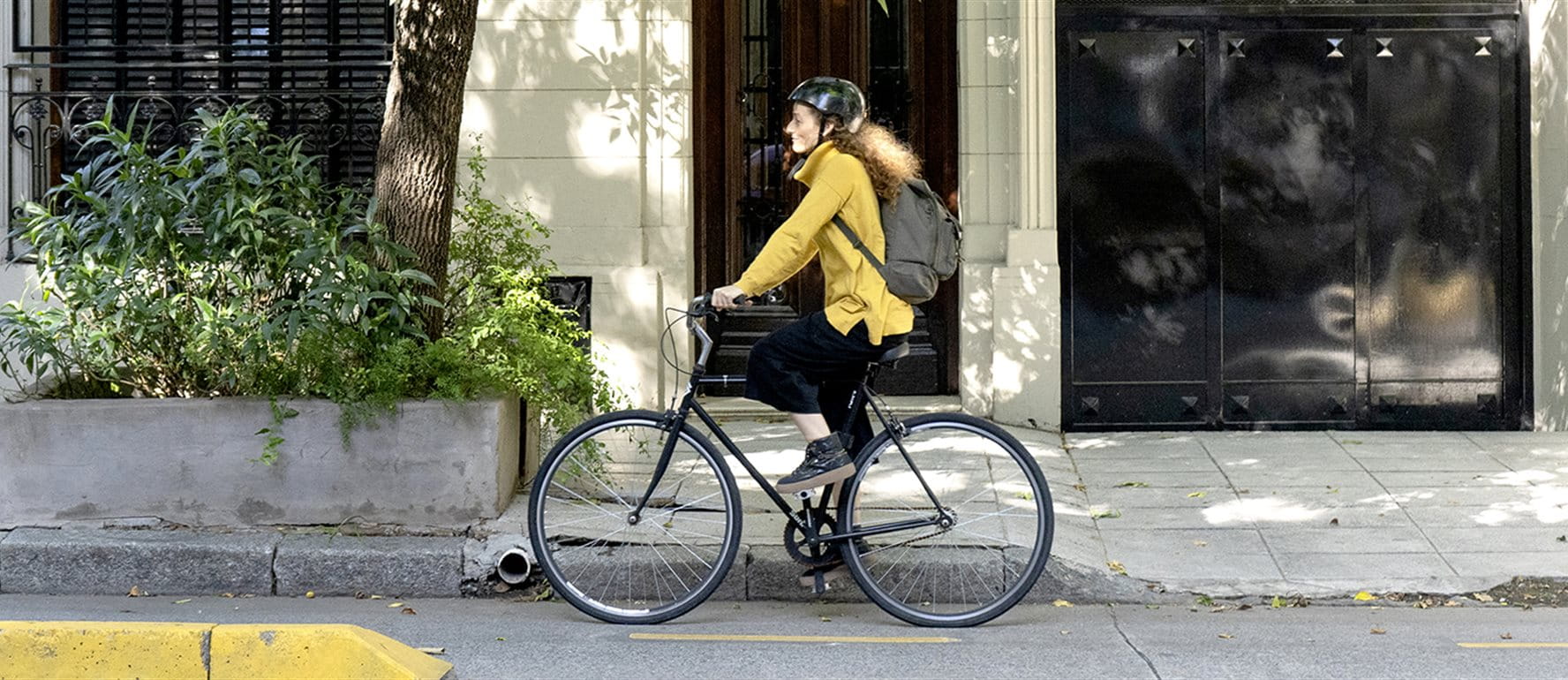 A person rides a bicycle on a sidewalk with planters. A person rides a bicycle on a sidewalk with planters.