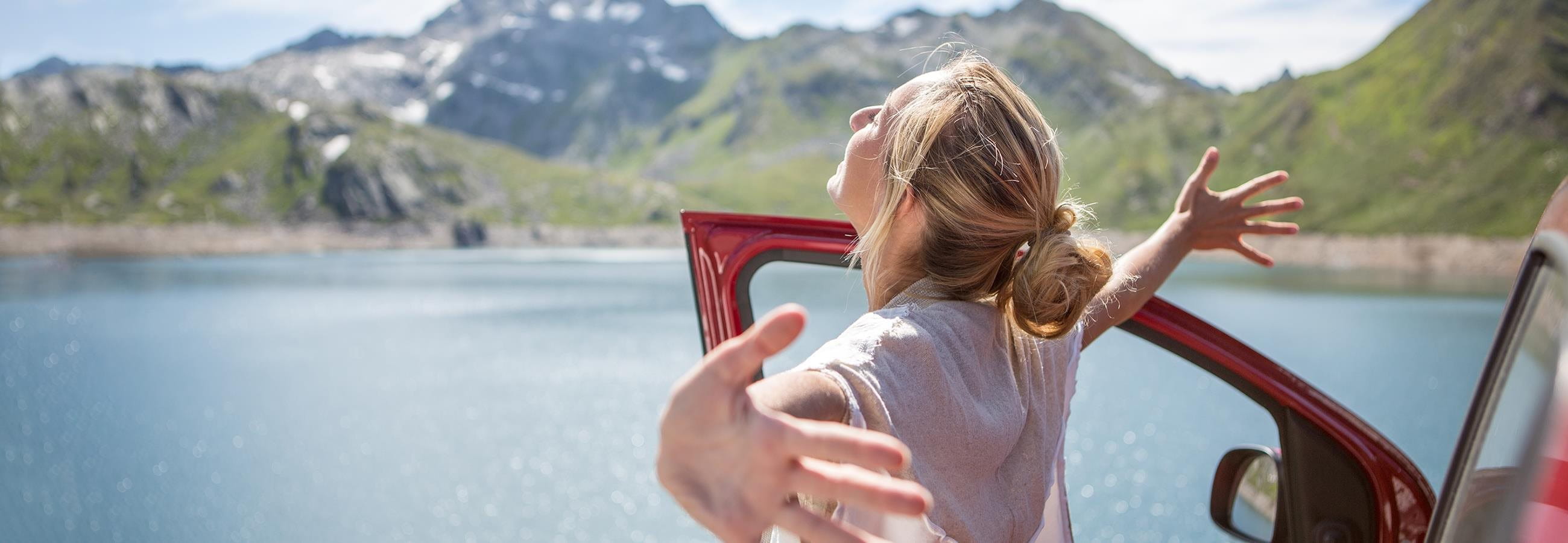 Woman standing in front of her car and spreading her arms out Woman standing in front of her car and spreading her arms out