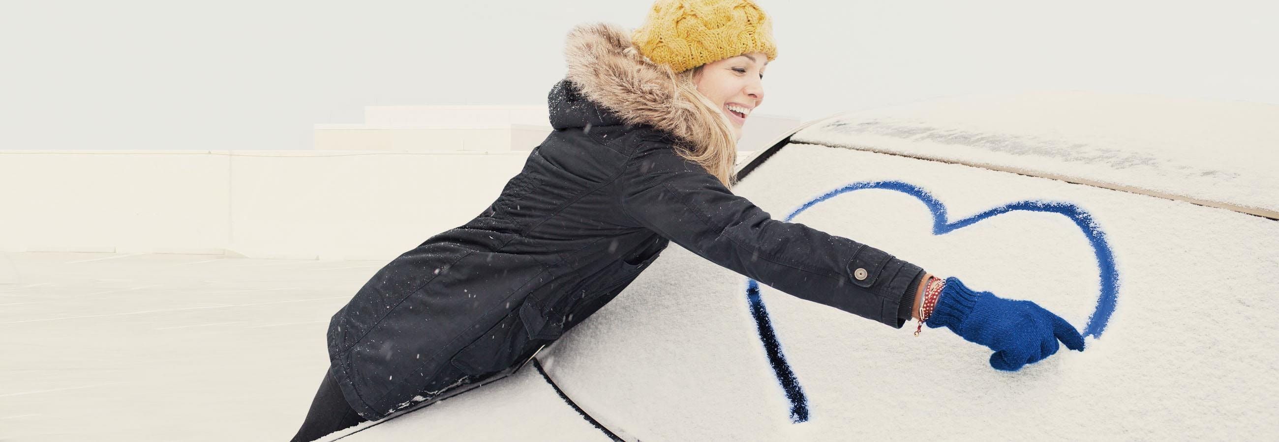 Woman draws heart on car window Woman draws heart on car window