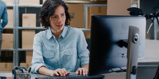 Woman sitting at a computer in a warehouse Woman sitting at a computer in a warehouse