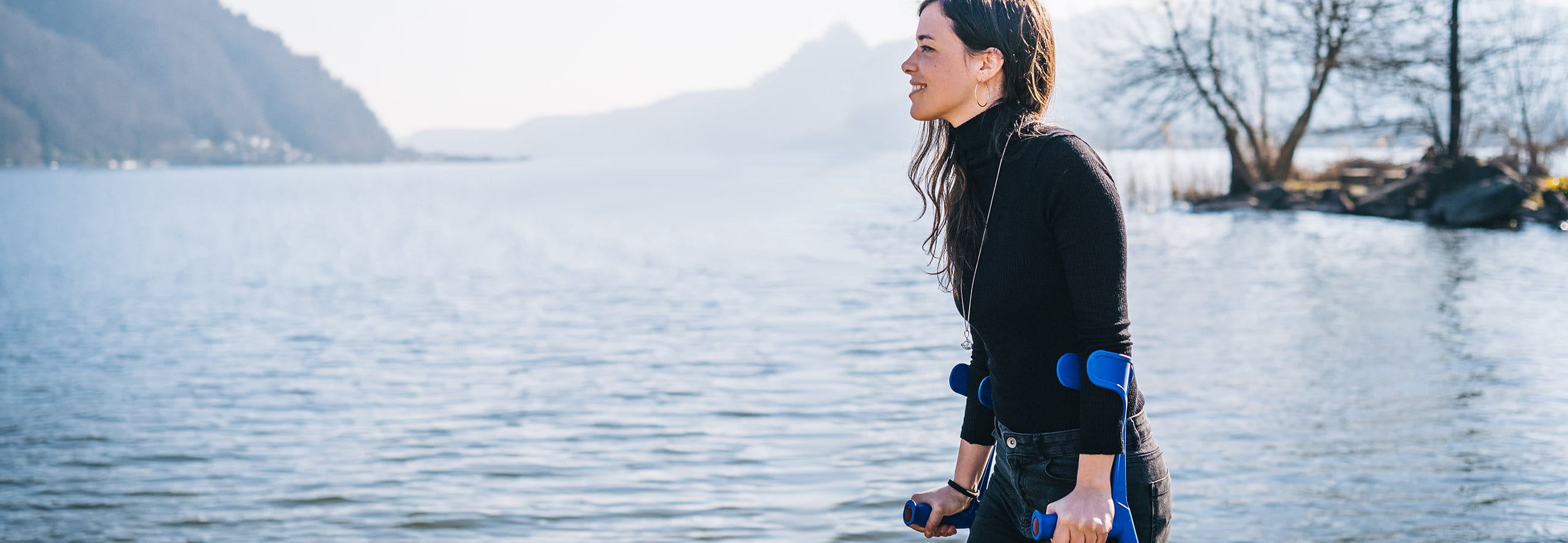 Une femme marche le long du lac avec des béquilles Une femme marche le long du lac avec des béquilles
