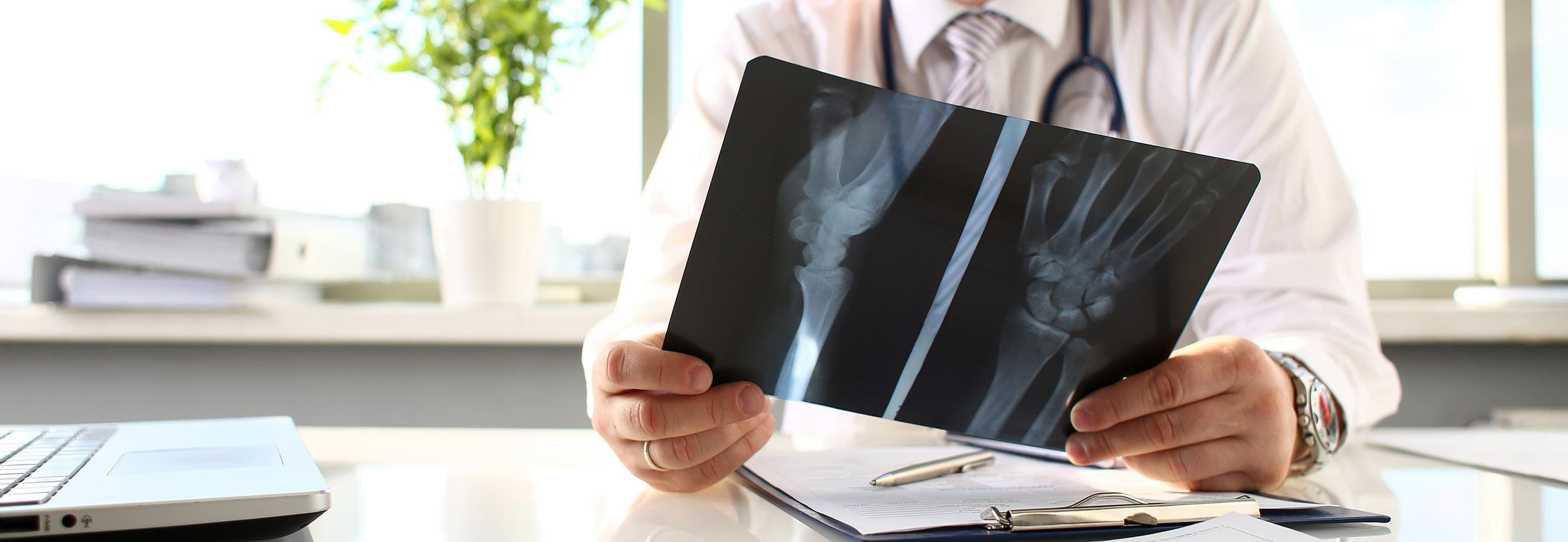 A doctor sits at the table and looks at an X-ray image A doctor sits at the table and looks at an X-ray image