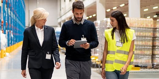 Three people are walking through a warehouse with a checklist Three people are walking through a warehouse with a checklist