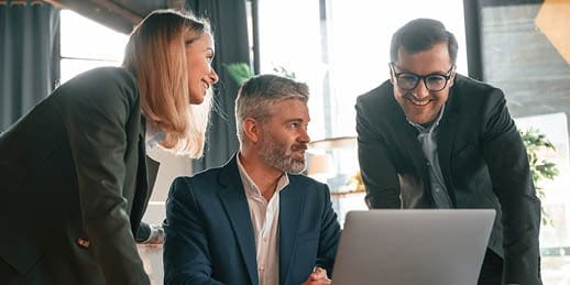 Drei Personen schauen in einen Laptop Drei Personen schauen in einen Laptop