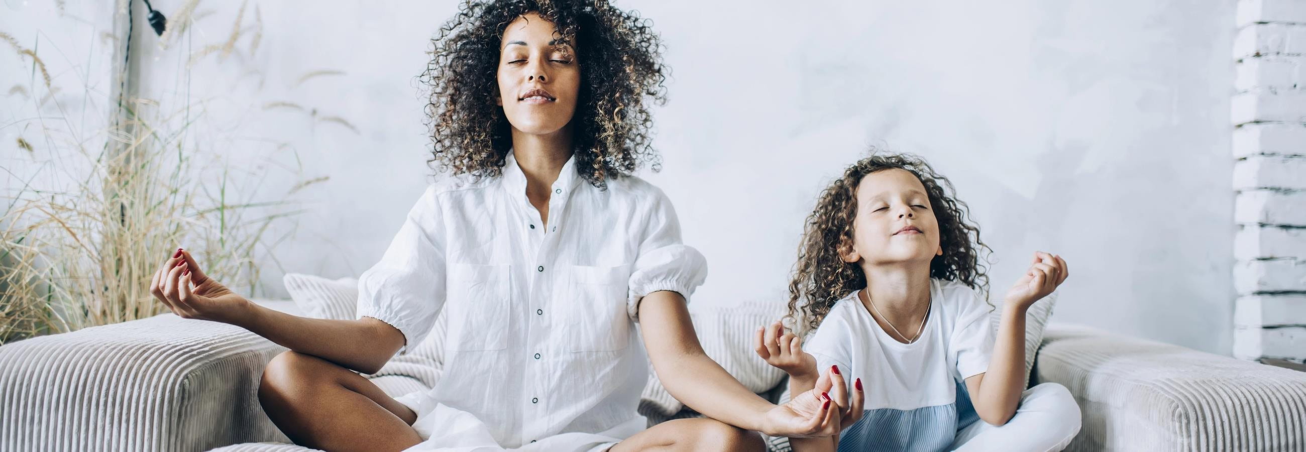 Mother and daughter doing yoga on sofa Mother and daughter doing yoga on sofa