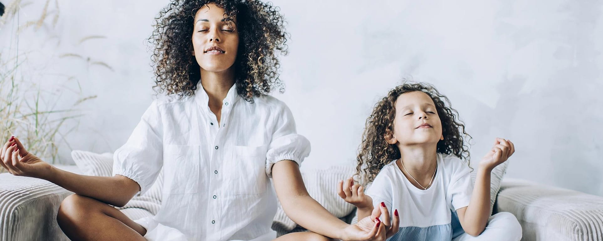 Mutter und Tochter machen Yoga auf dem Sofa Mutter und Tochter machen Yoga auf dem Sofa