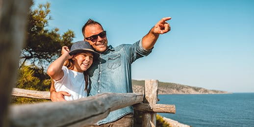 Father enjoys the view with his daughter by the sea Father enjoys the view with his daughter by the sea