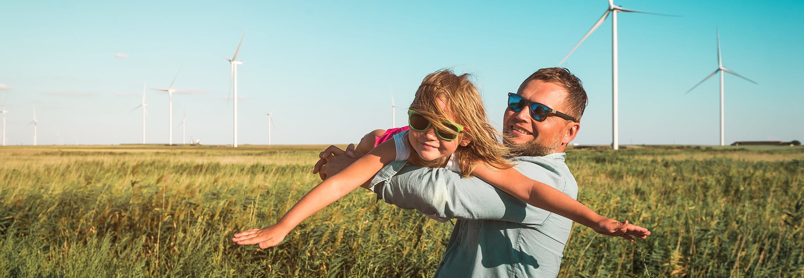 Man with child in a field in front of wind turbines Man with child in a field in front of wind turbines