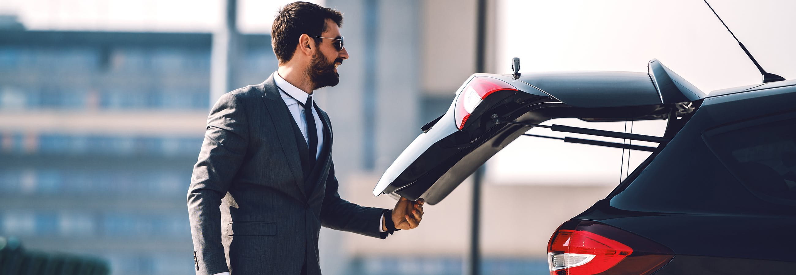 Man stands in front of the open trunk of his car Man stands in front of the open trunk of his car