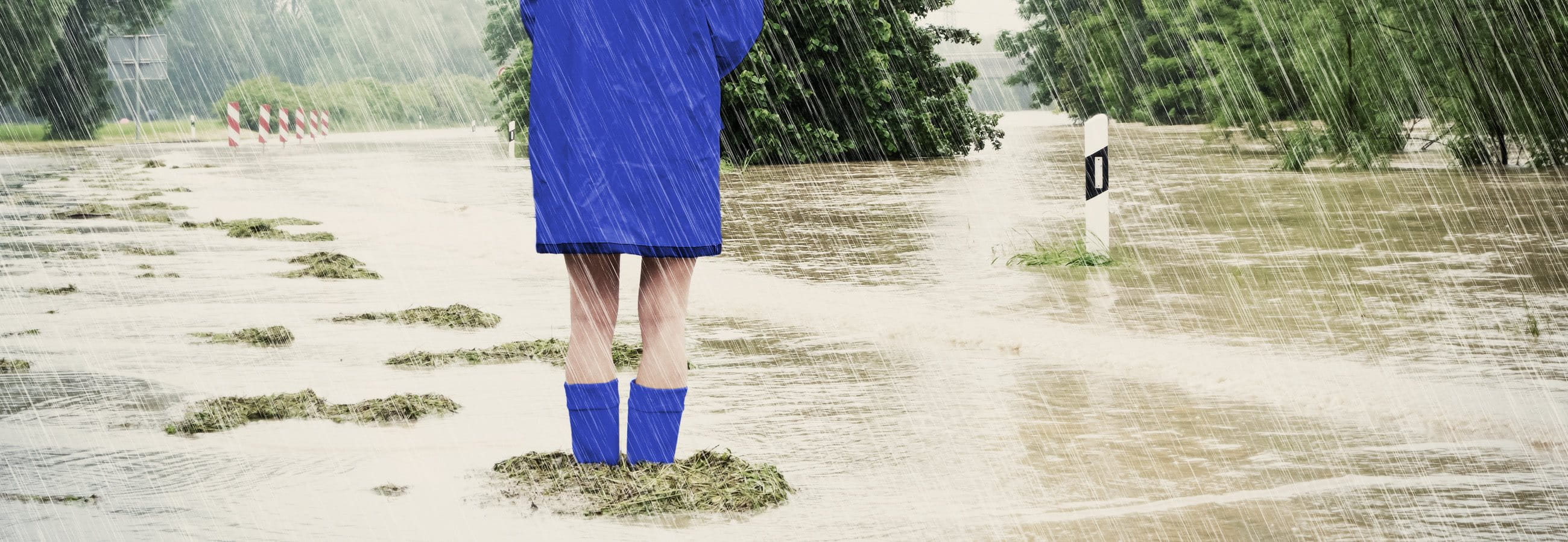 Woman standing in a flood wearing a raincoat and rubber boots Woman standing in a flood wearing a raincoat and rubber boots